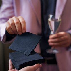 Black paper cocktail napkin being handed to customer