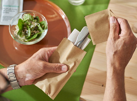 Sealed cutlery pocket being held by customer