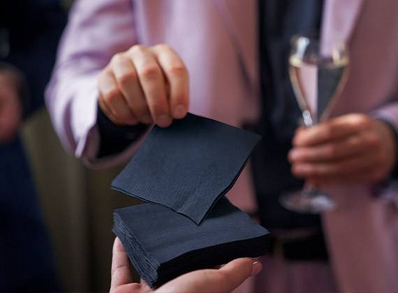 Black cocktail napkin being handed to customer