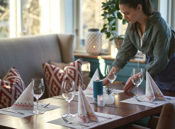 Waitress setting restaurant table with festive Nordic tableware