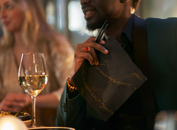 Man holding black napkin with metallic accents at a bar