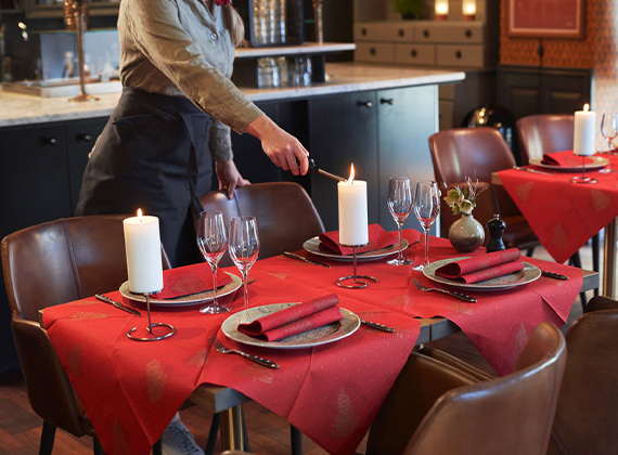 Waitress lighting a candle on a festive red restaurant table