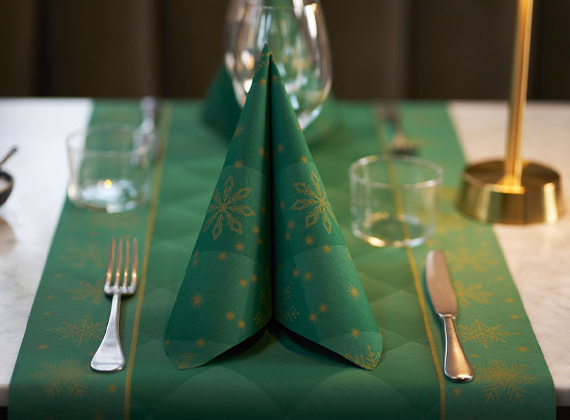 Festive dining table with green snowflake napkins, glassware and gold table lamp – ideal for showcasing Christmas tableware and seasonal venue styling.