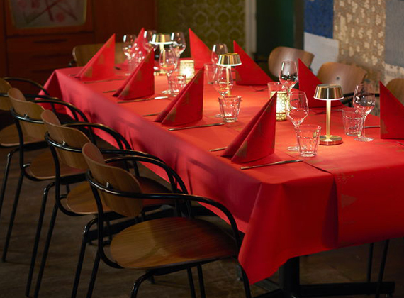 Elegant Christmas dining table setup with red tablecloth, folded napkins, LED candles – perfect for seasonal venue promotions and party bookings.
