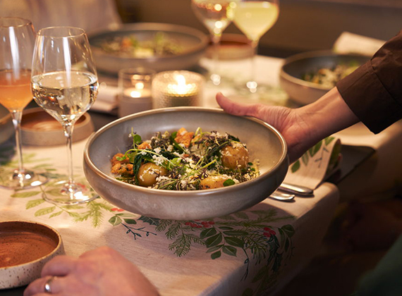 Festive table scene with mixed drinks, a bowl of garnished salad and winter greenery tableware – highlighting hospitality and seasonal dining.